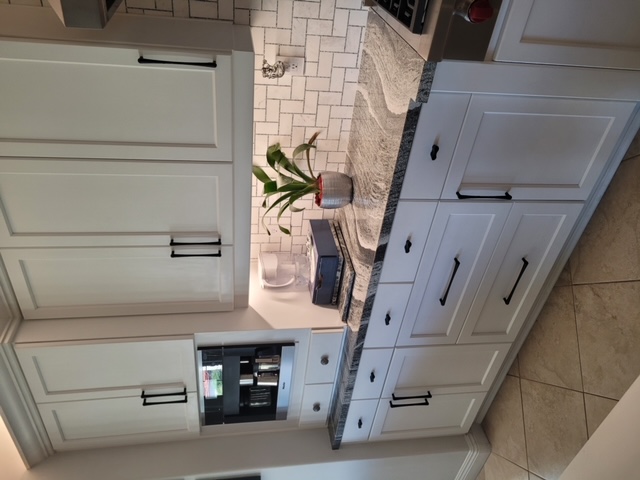 Refaced white kitchen cabinets with deep storage drawers and black hardware