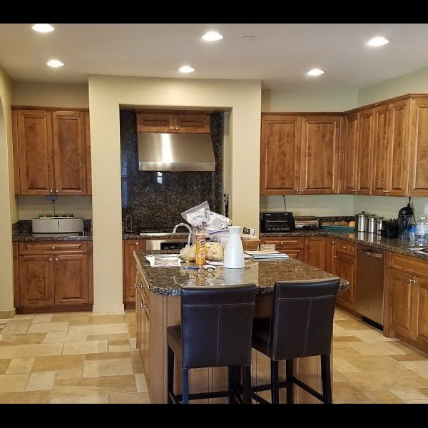 Kitchen before refacing, with warm maple raised-panel cabinets and dark granite countertops