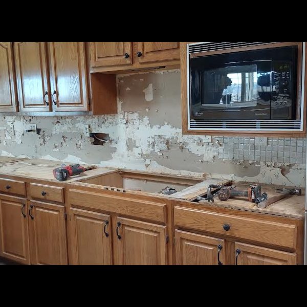 Kitchen mid-refacing, with the old countertops and backsplash removed from the original oak cabinets